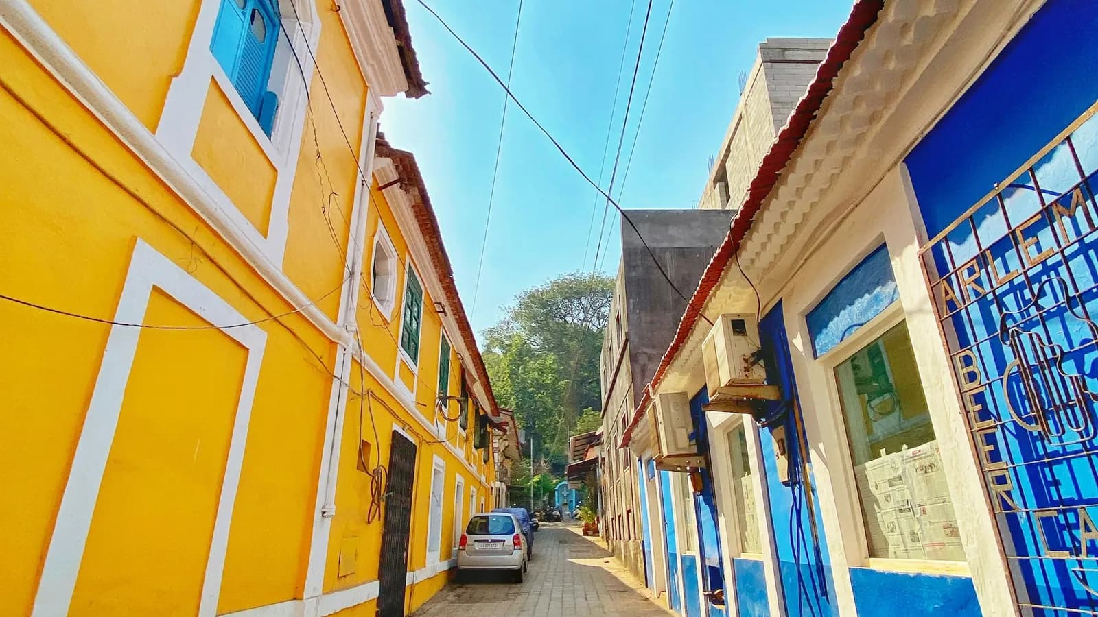 A narrow Goan street lined with yellow and blue Portuguese-era buildings